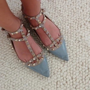 Valentino, strl 41 - Snygga grå ballerinaskor från Valentino med spetsig tå och dekorativa guldfärgade nitar. Skorna har remmar som ger en cool look och är perfekta för att lyfta vilken outfit som helst