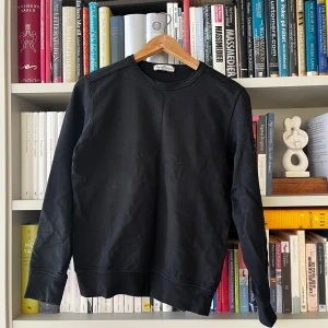 Svart tröja från Stone Island Junior - Säljer en stilren svart tröja från Stone Island Junior. Tröjan har långa ärmar och en rund halsringning. Den ikoniska Stone Island-loggan sitter på ärmen. *Junior storlek! lite mindre än S. 