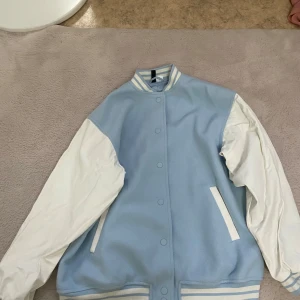 Ljusblå och vit bomberjacka från H&M - Säljer en ljusblå och vit bomberjacka från H&M. Jackan har vita ärmar, ljusblå kropp. Dem har användes endast en gång