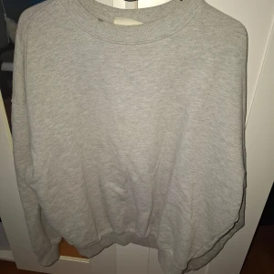 Grå sweatshirt från H&M Move - En basic grå sweatshirt från H&M Move. Tröjan har rund halsringning, långa ärmar och ribbade muddar vid ärmslut och nederkant. Perfekt för en avslappnad stil eller till träning.