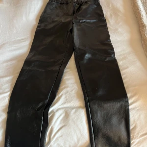 Svarta skinnleggings från Zadig & Voltaire - Snygga svarta leggings i skinnimitation från Zadig & Voltaire. Byxorna har resår i midjan och en stilren, tight passform som ger en cool look. Perfekta att styla med en oversized tröja eller kavaj.