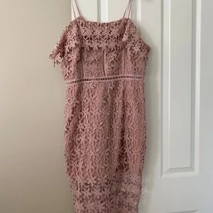Rosa spetsklänning från New Look Premium - Säljer en romantisk rosa spetsklänning från New Look Premium. Klänningen har smala axelband, blommigt broderat spetsmaterial och dragkedja bak. Perfekt för sommarens tillfällen och har en feminin, figurnära passform.