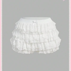 Vita volangshorts med spets och rosett - Supersöta vita shorts med flera lager volanger i spets och en liten rosett framtill i midjan. Perfekta för dig som gillar en romantisk och lekfull stil 🩷