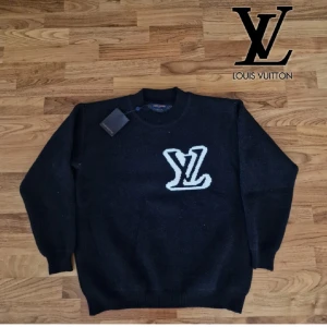 tröja från Louis Vuitton - Snygg mörkgrå tröja från Louis Vuitton med ett stort vitt LV-märke på framsidan och baksidan. Tröjan har en rund halsringning och är perfekt för en stilren look. Pris kan diskuteras