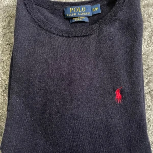 Ralph Lauren tröja i merinoull - Elegant mörkblå Ralph Lauren tröjan i materialet merinoull. Tröjan är egentligen i storlek small men den passar mer som extra small! Förutom det är det en fin och skön tröja som passar perfekt nu inför sommaren. 