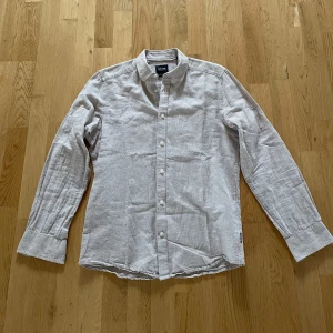 Beige linneskjorta från Only & Sons - Säljer en stilren beige skjorta i linne från Only & Sons. Skjortan har lång ärm, klassisk krage och knäppning framtill. Passformen är slim och materialet är svalt och skönt linne – perfekt för varmare dagar.