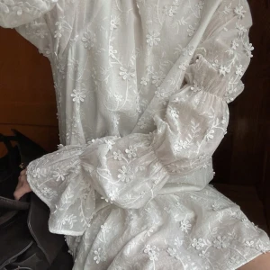 Vit klänning Nakd - Superfin vit klänning från NAKD med broderade blommor och långa puffärmar. Klänningen har öppen rygg med knytband. Perfekt till studenten eller konfirmationen💕