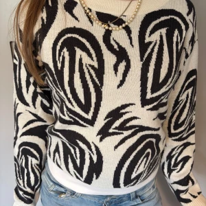 Svartvit stickad tröja från H&M - Säljer en stickad tröja från H&M i svartvitt abstrakt mönster. Tröjan har lång ärm och rund halsringning, perfekt för dig som vill sticka ut lite extra. Passar till jeans eller kjol.
