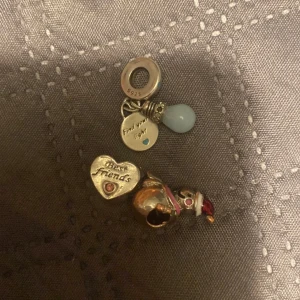 Pandora berlock 'Best Friends' med glödlampa - Säljer en söt Pandora berlock i silver med texten 'Best Friends' och 'Find your light'. Berlocken har ett hjärta med liten blå och röd detalj samt en glödlampa i ljusblått. Perfekt som present till en vän.