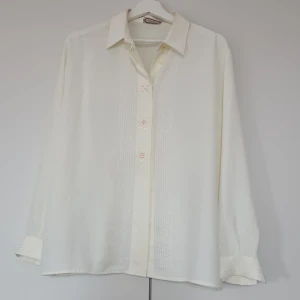 Vit blus med broderi och pärlor från Modital - Snygg vit blus från Modital med långa ärmar. Framsidan har dekorativa broderier och pärlor längs knappraden. Klassisk krage och knappar framtill. Perfekt för dig som gillar detaljer och en stilren look.