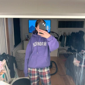 Lila hoodie från Hoodrich - Säljer en lila hoodie från Hoodrich med vit text framtill. Tröjan har huva med dragsko och en stor magficka. Perfekt för dig som gillar streetwear och vill ha en skön och snygg hoodie.
