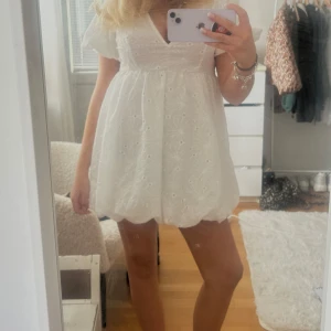 Vit kort klänning med puffärm!!! - Supersöt vit kort klänning med puffärmar och v-ringning. Klänningen har broderade blommor och en ballongformad kjol. Perfekt för sommarens alla tillfällen typ student eller skolavslutning!!!