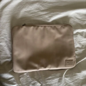 Beige datorfodral från ZIGN - Säljer en stilren beige datorfodral från ZIGN med dragkedja och innerfack. Väskan är tillverkad i syntetmaterial och passar perfekt för att bära din laptop eller dokument. Enkel och minimalistisk design med diskret logga på insidan. Finns defekter på den som man ser på sist bilden. Kan även finnas lite små märken här och där då jag använt den🩷 skriv om du vill att jag skickar mer bilder på just dessa effekter 
