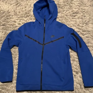 Nike tech fleece hoodie - Jag säljer min näst intill oanvända Nike tech fleece hoodie som jag köpte för någon månad sedan. Jag väljer att sälja den på grund av att jag köpte fel storlek! Den är i väldigt bra skick och i storlek M. Priset går absolut att diskutera och det är bara att höra av sig om man har någon fråga☺️