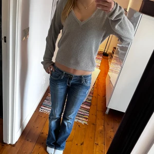 Grå ribbad stickad tröja från NA-KD - Säljer en ljusgrå stickad tröja från NA-KD i storlek XXS. Tröjan har v-ringning, långa ärmar och är ribbad för en snygg och enkel look. 