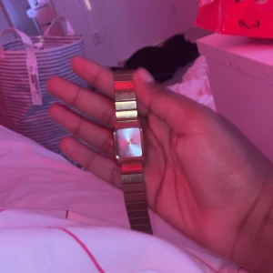 Guldig fyrkantig klocka med länkarmband - Säljer en stilren klocka i guld med fyrkantig urtavla och matchande länkarmband. Urtavlan är ljus med minimalistisk design och metallisk känsla. Perfekt accessoar för dig som gillar klassisk men ändå modern stil.