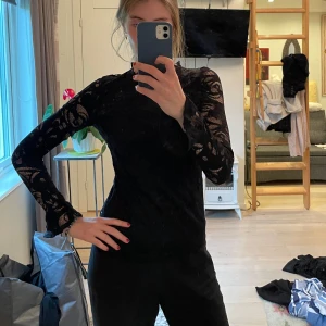 Svart spetsblus från Gina Tricot - Säljer en svart långärmad spetsblus från Gina Tricot i storlek S. Blusen har ett genombrutet blommigt spetsmönster och hög hals. 