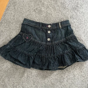 Jeanskjol med volanger - Supersöt mörkblå lågmidjad jeanskjol från Mexx med volanger och hjärtformade fickor bak. Kjolen har knappar framtill och ett hjärta, söta rosa och beige sömmar. Säljer på grund av för liten, skulle säga storlek XS-XXS. Skriv vid mått och frågor!🤗💗 