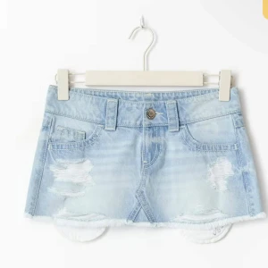 Ljusblå jeanskjol med slitningar - Trendig ljusblå jeanskjol i kort modell med slitna detaljer och rå kant nertill. Klassisk femficksdesign och bälteshällor. Perfekt för dig som gillar en avslappnad och cool stil. Så snygg💕 Slutsåld online!!!