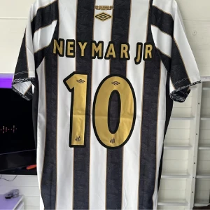 Santos Neymar Jr #10 Umbro fotbollströja - Santos FC fotbollströja med Neymar Jr.Perfekt för sommaren. Priset går att diskutera, storlek M. Skriv för frågor! Exklusiv tröja då reklamen är borttagen för att göra tröjan snyggare! Extremt svår att få tag på! 