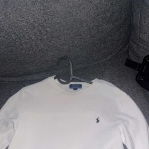 Vit långärmad tröja från Polo Ralph Lauren - Vit långärmad tröja från Polo Ralph Lauren med klassisk rund hals och den ikoniska broderade loggan på bröstet. Tröjan är i mjuk bomull och har en stilren, enkel design som funkar till allt. Perfekt för dig som gillar clean och tidlös stil. Pris Kan gå ner I snabbis affär.