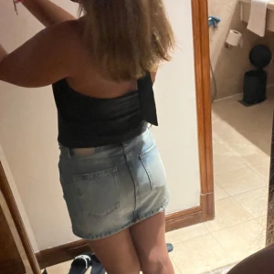 Jeanskjol  - Säljer en ljusblå jeanskjol från Pull&Bear med slitna detaljer och fransig nederkant. Kjolen har klassisk femficksdesign, bälteshällor och knappstängning. Perfekt för en chill och trendig look i sommar. 