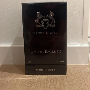 Parfums de Marly Layton Exclusif 125ml - Lyxig parfym från Parfums de Marly, Layton Exclusif Edition Royale. Flaskan rymmer 125ml och kommer i en elegant svart förpackning med silverdetaljer och klassiskt emblem. Tillverkad i Frankrike och innehåller bland annat alkohol, vatten och olika doftämnen.