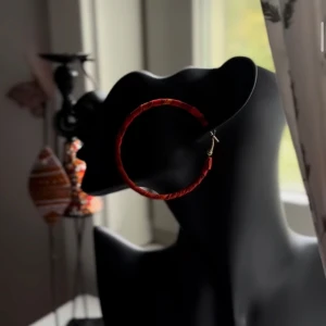 Stora röda hoops från Shop with Tyra - Snygga stora hoop-örhängen i rött med inslag av orange. Örhängena har en rund form och är klädda i tyg för en unik look. Perfekta för dig som vill sticka ut och addera färg till din stil. Följ oss på Instagram; @shop_with_tyra