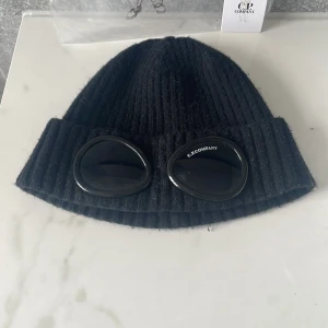 Svart C.P. Company Goggle Beanie - Tjenare, säljer nu min C.P Company mössa för att jag har tappat suget för den. Jätte fin med påse och en lapp typ där de står C.P Company. Några små repor på glaset men dem ser man bara om man kollar riktigt noga med ljus. Perfekt till en person som gillar att ha mössa på sig inne och ute. Priset går att diskutera