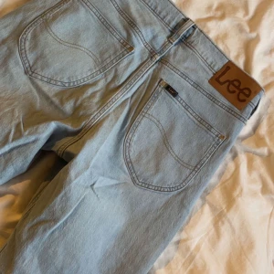 Ljusblå jeans från Lee W29 L30 - Säljer ett par ljusblå jeans från Lee i klassisk femficksmodell. Jeansen har raka ben, normal passform och är tillverkade i mjukt denimtyg. Snyggt Lee-läderpatch bak och diskreta sömmar. Perfekta för en chill och stilren look.