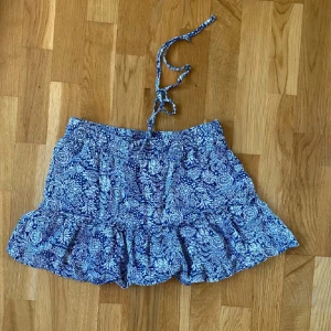 Mönstrad kjol från Zara - Supersöt blåvit kortkjol från Zara med blommigt mönster och volangkant. Kjolen har knytband i midjan och även inbyggda shorts! Använd väldigt få gånger!