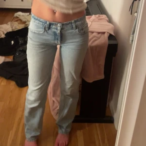 Ljusblå raka jeans låg midja - Säljer ett par ljusblå jeans med låg midja och klassisk rak passform. Jeansen har fem fickor, bälteshällor och stängs med dragkedja och knapp. Perfekta för en avslappnad och trendig look.