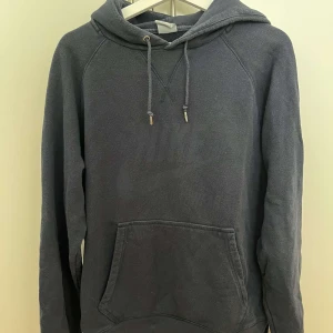 Mörkgrå hoodie från Nike - Säljer en mörkgrå hoodie från Nike med diskret logga framtill. Tröjan har huva med snörning och en stor magficka. Perfekt för dig som gillar en avslappnad och sportig stil. Långärmad och i mjuk bomullsblandning.