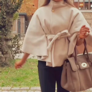 Beige kappa med bälte och vida ärmar - Säljer en superfin beige kappa med knytbälte i midjan och vida, trekvartsärmar. Supersnygg och väldigt trendig poncho som är superfin. Den är endast använd 1 gång 💌Så så snygg!!!😍🥹