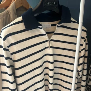 Randig pikétröja från These Glory Days - Snygg randig pikétröja från These Glory Days i storlek S. Tröjan är vit med marinblå ränder, har en krage och half zip-dragkedja. Skriv vid frågor🙌🏽