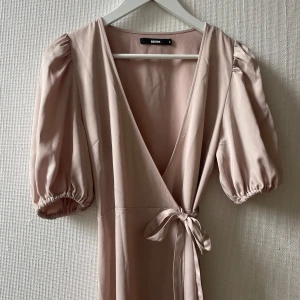 Beige omlottklänning från Bik Bok - Supersöt beige omlottklänning från Bik Bok med puffiga korta ärmar och knyt i midjan. 