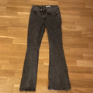 Bootcut jeans från Gina Tricot, svart - Snygga svarta bootcut jeans från Gina Tricot, modell Perfect Jeans. Jeansen har en klassisk femficksdesign, hög midja och råa kanter nertill för en trendig look. Materialet är jeans i tvättad svart nyans med lätt slitning.