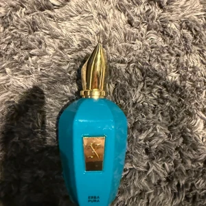 Blå parfymflaska från Xerjoff - Säljer en lyxig parfym från Xerjoff i en iögonfallande blå flaska med gulddetaljer. Flaskan har en unik form med en elegant guldfärgad kork. Perfekt för den som vill ha något speciellt i sin doftsamling.
