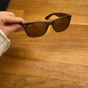 Bruna solglasögon från Ray-Ban - Snygga bruna solglasögon från Ray-Ban gammal design med klassisk design. De har mörka linser och en stilren båge som passar perfekt för soliga dagar. Perfekt accessoar för att ge din stil en cool touch.