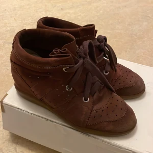 Vinröda sneakers från Isabel Marant - Snygga Vinröda Isabel Marants. Kilklack. Dustbag och lådan ingår, lådan är dock sliten. Obs. De ser brunare ut på bild än vad de är irl. 