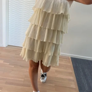 Beige/ ljusgul axelbandslös klänning - Säljer en chic beige / ljusgul/champagne färgad axelbandslös klänning med flera lager av volanger. Perfekt för en somrig look. Klänningen har en kort längd och ger en luftig känsla. Passar mig som bär xs/s!! OBS FÖRSTA BILDEN ÄR ENDAST LÅNAD OCH ENDAST EN LIKNANDE KLÄNNING 