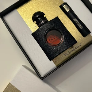 Yves Saint Laurent Black Opium parfymset - Lyxigt parfymset från Yves Saint Laurent med Black Opium doft. Innehåller en elegant svart glittrande flaska och en matchande mascara. Perfekt för den som älskar en djärv och sensuell doft. Förpackningen har en stilren design med guld och svart.