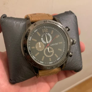 Herrklocka med brun läderrem från Wendel - Snygg herrklocka från Wendel med en brun läderrem och en stilren urtavla. Klockan har en silverfärgad boett och flera funktioner som datumvisning och kronograf. Perfekt för den som vill ha en kombination av stil och funktion.