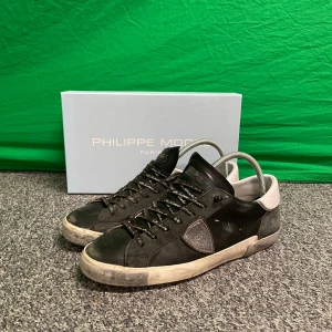 Svarta sneakers från Philippe Model - Snygga svarta sneakers från Philippe Model med vita detaljer och snörning. Skorna har en klassisk design med en robust sula och är perfekta för en stilren look. Kan diskuteras med pris 