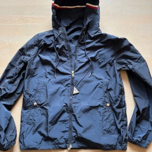 Mörkblå vindjacka från Moncler - Säljer en helt ny moncler vindjacka. Perfekt nu får våren och sommaren, jackan är helt äkta knappt använd. Köpte jackan för 9000 och passar ej min storlek. Hör av er om ni vill ha mer äkta bevis och har absolut kvitto om ni vill se. Hör av er!