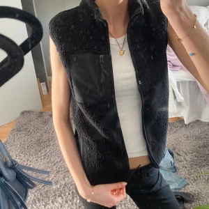Svart teddy väst - Säljer en mysig svart fleeceväst med dragkedja framtill och en praktisk bröstficka med dragkedja. Använd max 1 gång. Strl 140 barn storlek men passar en xs/s.  Inga defekter. Hör av dig vid fler frågor❤️