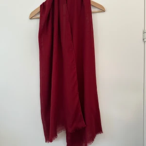 Röd halsduk / sjal / scarf - Snygg röd halsduk med en lätt glittrig effekt. Perfekt för att ge en färgklick till din outfit. Den har en enkel design med korta fransar i kanterna.