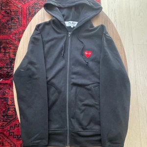 Svart CDG hoodie - Svart CDG kofta med röd logga. Storlek M, väldigt bra skick. Har flera kläder på min profil från CDG och andra märken. Pris kan diskuteras!