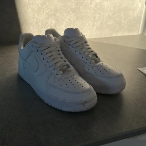 Vita Nike Air Force sneakers - Säljer ett par klassiska vita Nike Air Force sneakers. De har en stilren design med snörning och perforerade detaljer på ovansidan för ventilation. Perfekta för en avslappnad och trendig look. Använd max 5 gånger så är i väldigt bra skick, låda och crease skydd följer med, pris kan diskuteras vid snabb affär.