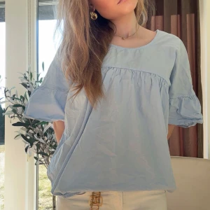 Ljusblå blus - Säljer en söt ljusblå blus med volangärmar. Blusen är perfekt till sommarn! En fin sommar färg som passar till allt! En fin o trendig tröja som inte säljs längre😻